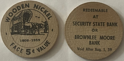 Front and back of wooden quarter coin showing covered wagon scene dated 1909-1959, face value 5¢, redeemable at Security State
