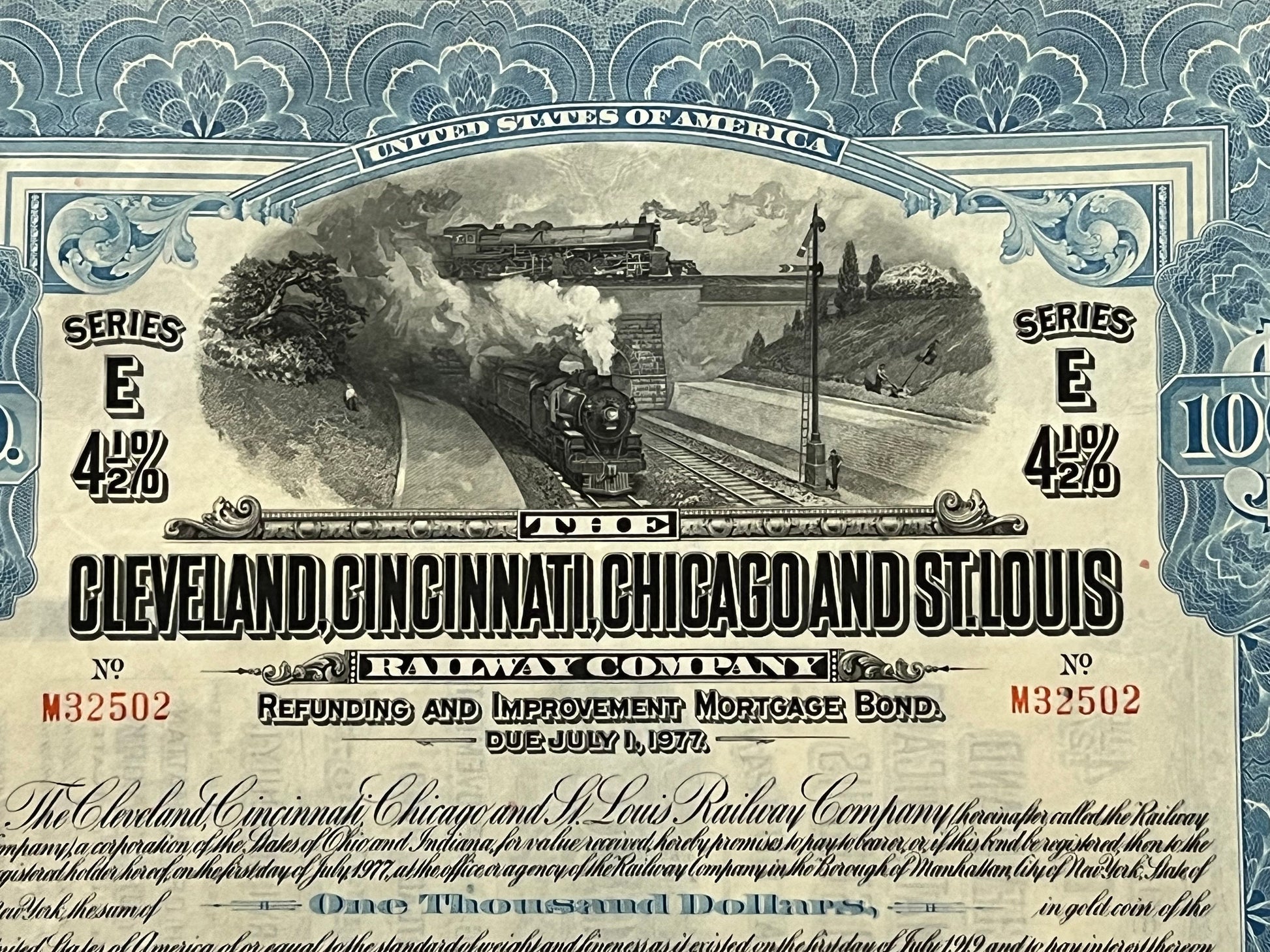 Antique railroad bond certificate with ornate blue border, steam locomotive engraving, "Series E 4½%" text, and "$1000" denom