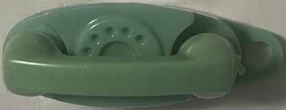 Overhead view of a vintage green plastic miniature telephone keychain with rotary dial and handset, shown against white surfa