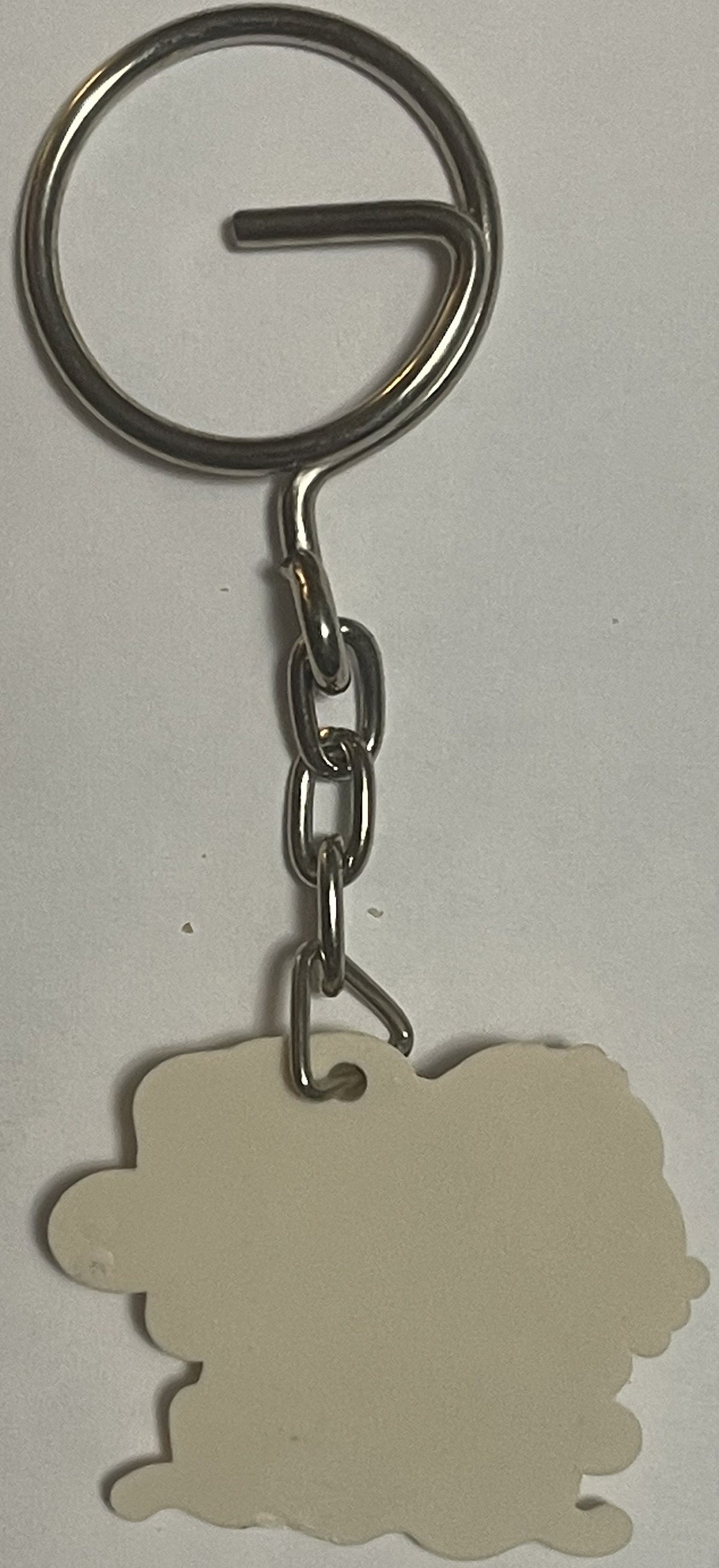 Cream-colored Hello Kitty keychain with scalloped edges hanging from metal split ring and chain against white background