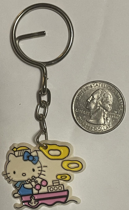 Vintage Hello Kitty sailor boat keychain with blue bow and yellow sail next to US quarter for scale