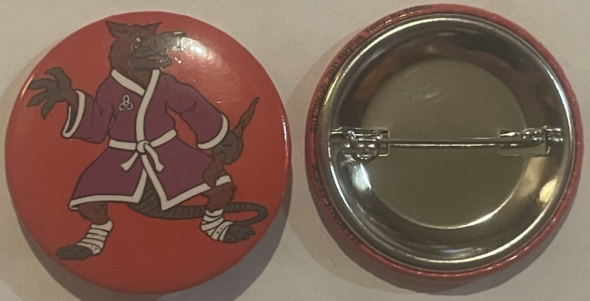 Front and back of red circular pinback button featuring brown cartoon rat character in purple robe with white trim