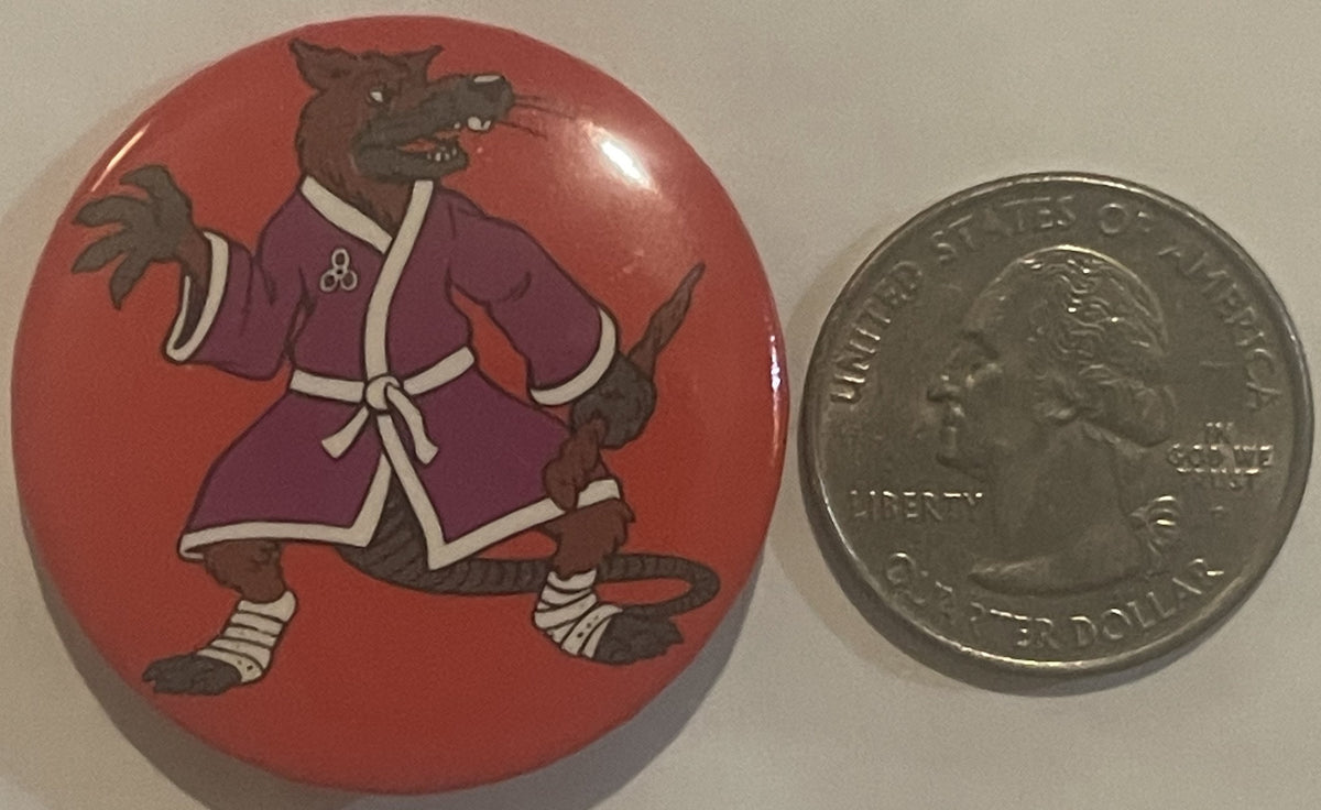 Circular red pinback button showing brown rat in purple robe next to quarter for scale