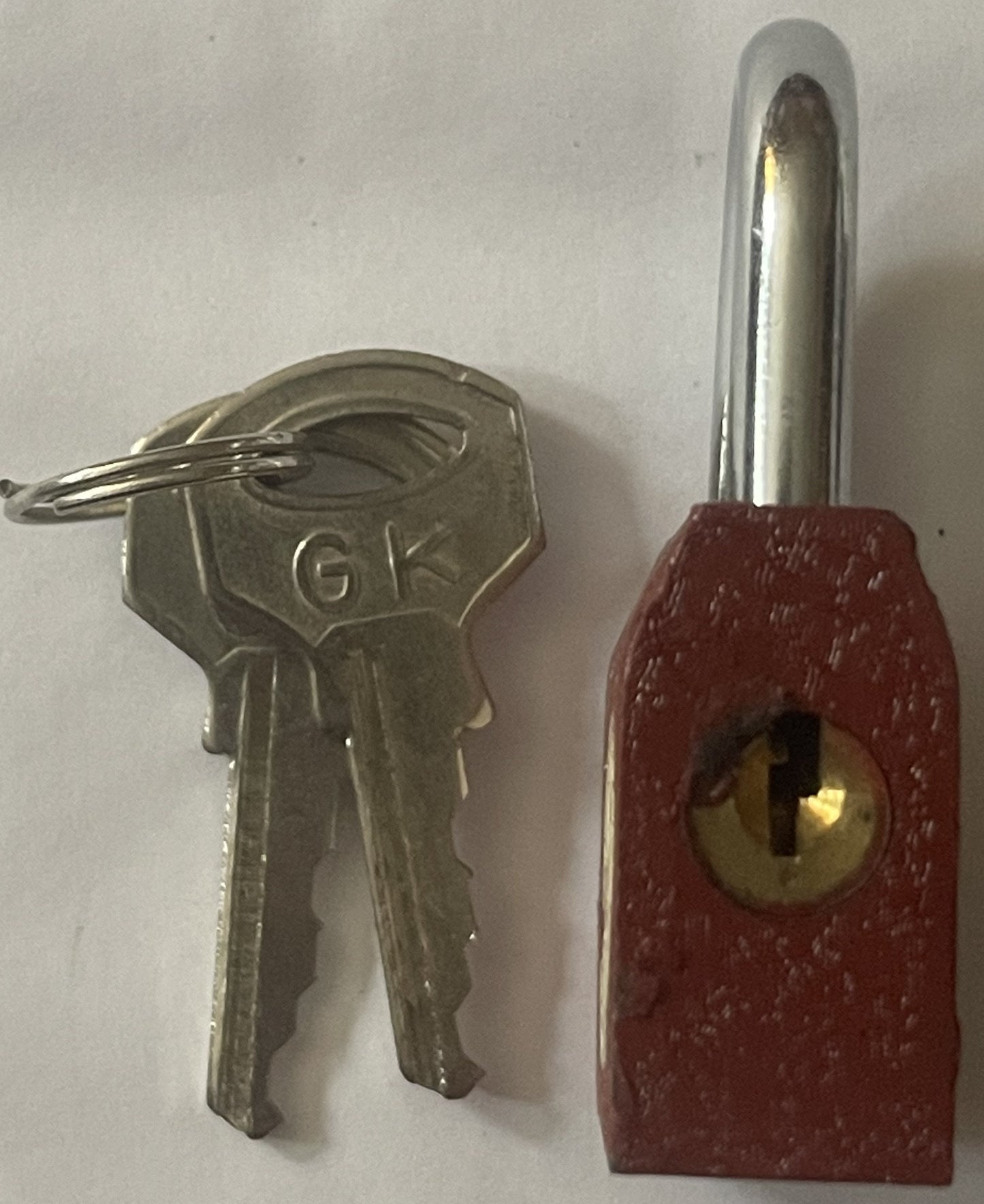Vintage GoldKey padlock with red metal body and chrome shackle displayed next to silver key on white background