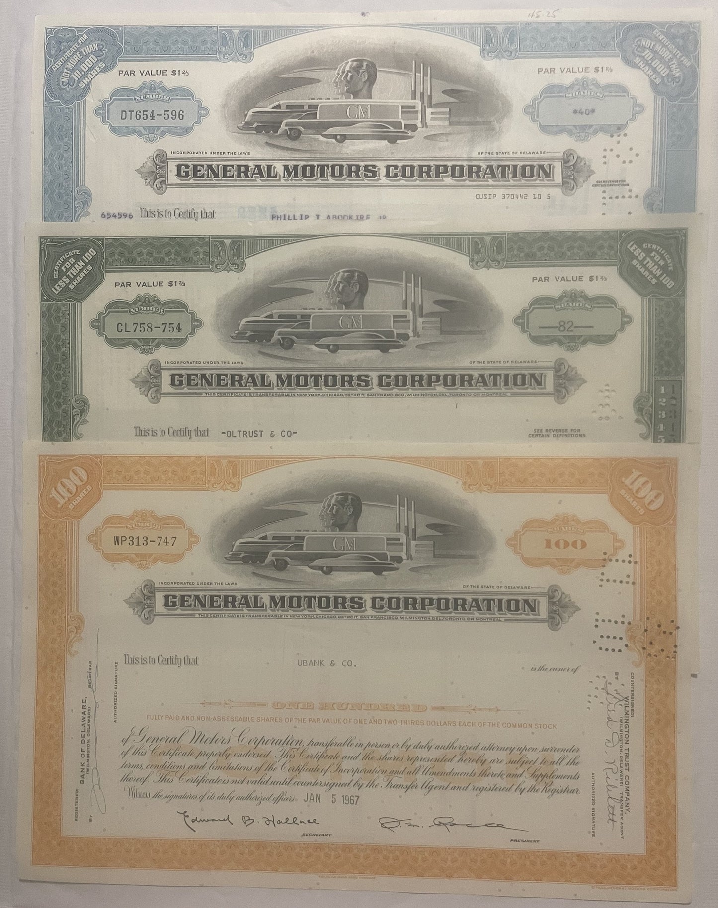 Three General Motors Corporation stock certificates from the 1950s-80s featuring streamlined locomotive vignettes, displayed 