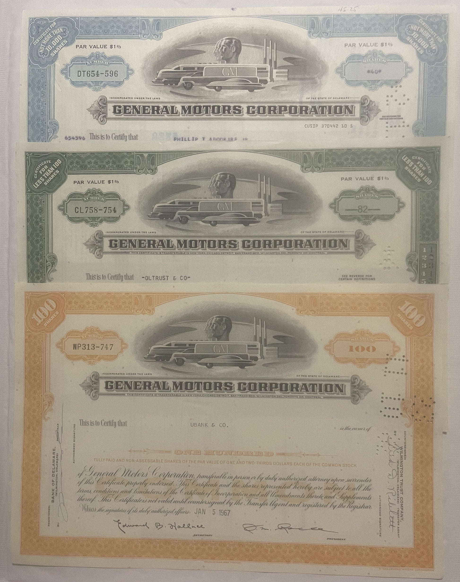 Three General Motors Corporation stock certificates from the 1950s-80s featuring streamlined locomotive vignettes, displayed 