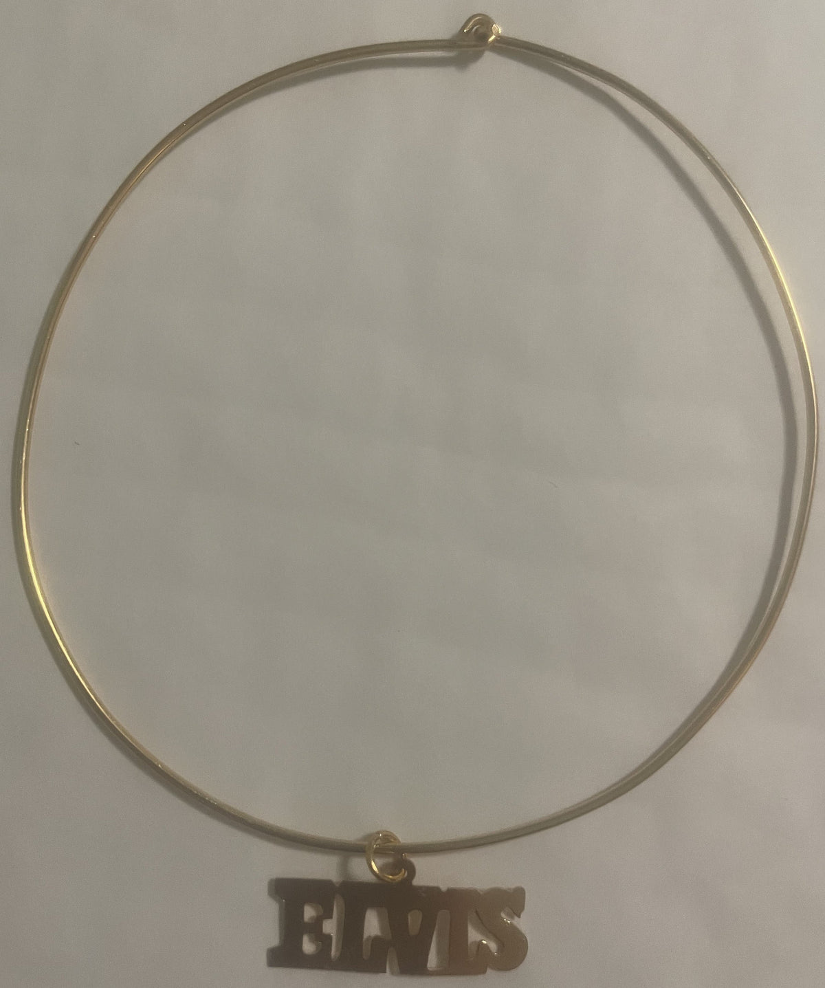 Gold-tone choker necklace with "ELVIS" nameplate charm pendant displayed flat against white background