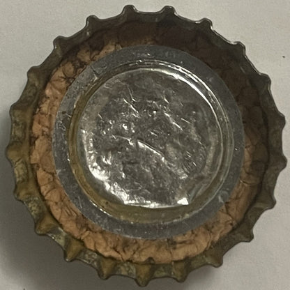 Vintage metal bottle cap with scalloped edges, showing embossed portrait profile and text, centered on white background with 