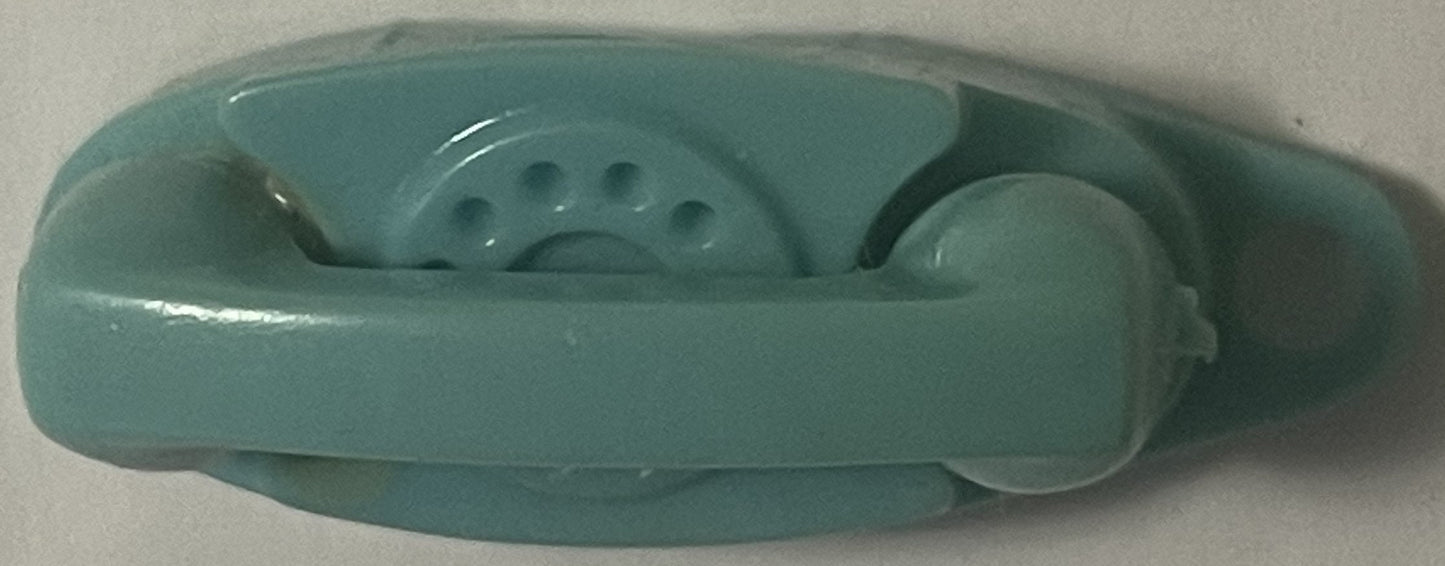Teal plastic vintage telephone keychain charm shown from above against white surface, displaying rotary dial and handset deta