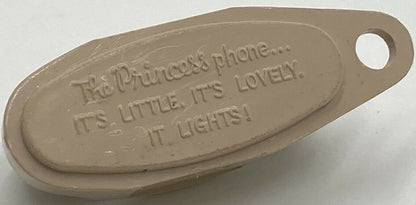 Cream-colored plastic keychain with embossed text reading "The Princess phone... it's little, it's lovely, it lights!" shown 