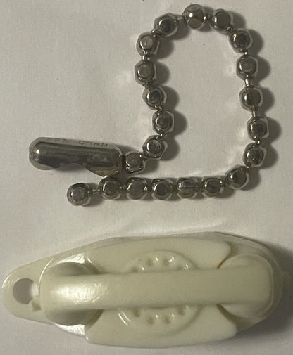 Vintage ivory plastic rotary phone keychain with metal ball chain above cream-colored phone base shown against white backgrou