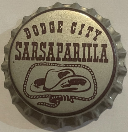 Vintage bottle cap with corrugated metal rim featuring "Dodge City Sarsaparilla" text and illustrated cowboy hat design
