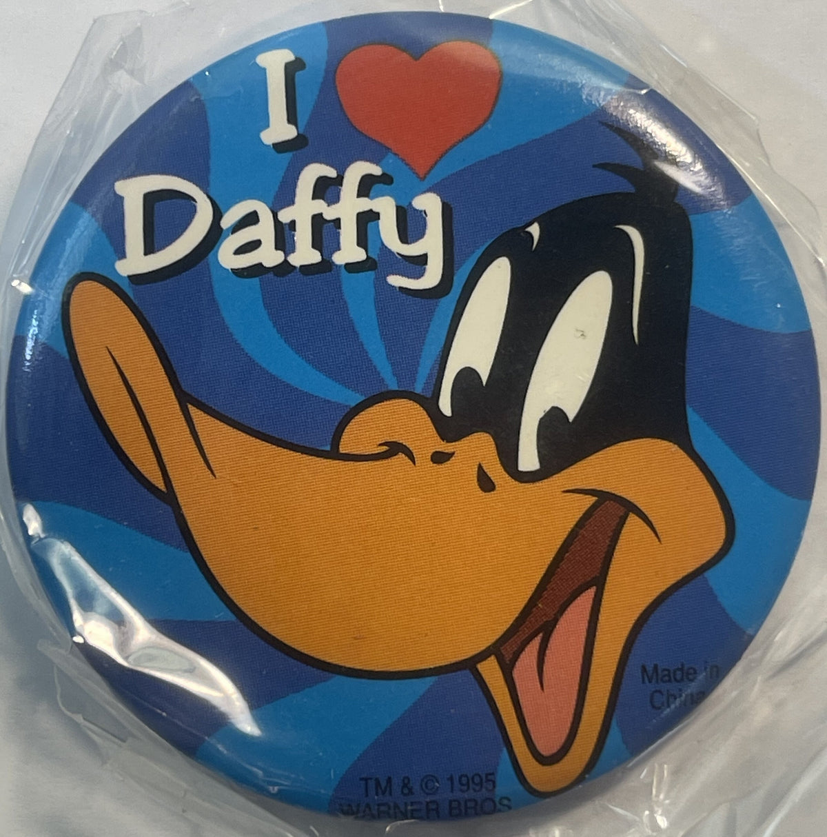 Circular pin featuring Daffy Duck with open mouth and tongue out, text reading "I ❤ Daffy" on blue background, Warner Bros co