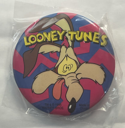 Unopened circular pin in clear plastic package featuring Wile E. Coyote cartoon character on red and blue checkered backgroun
