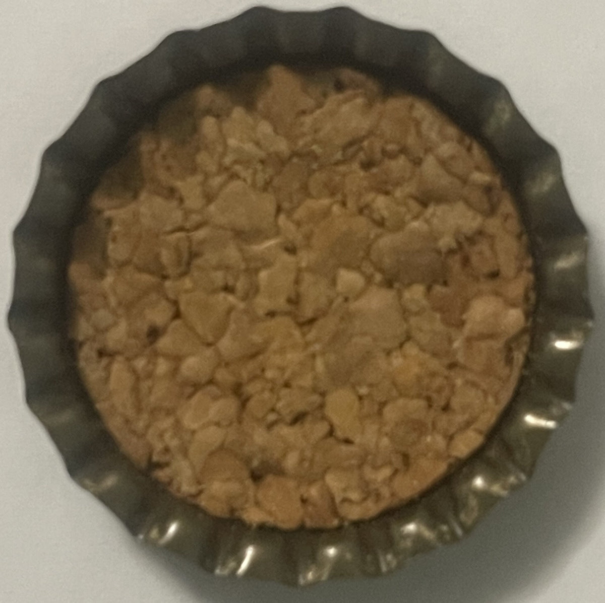 Vintage cork bottle cap with ridged metal edges shown from above on white background, tan cork interior visible