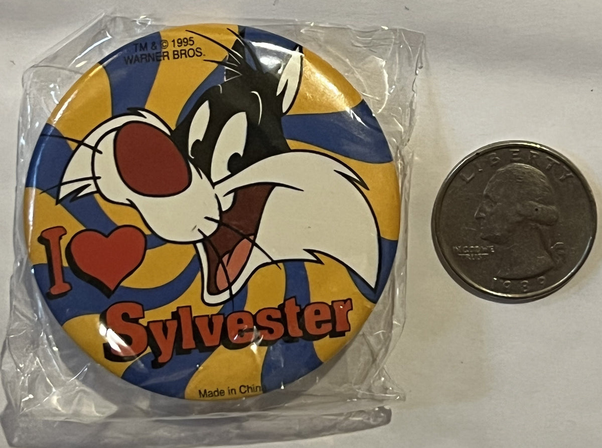 Unopened 1995 Warner Bros Sylvester pin in plastic packaging with quarter for scale, showing cartoon cat with heart and blue-