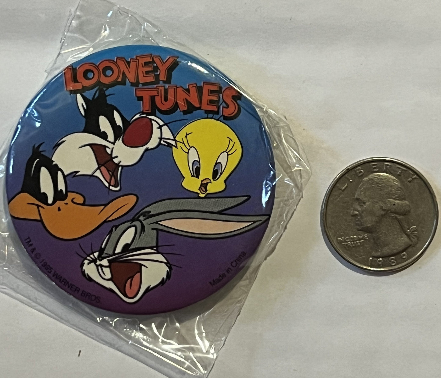 Unopened Looney Tunes pin in clear plastic package showing cartoon characters Bugs Bunny, Daffy Duck, Tweety, and Sylvester o
