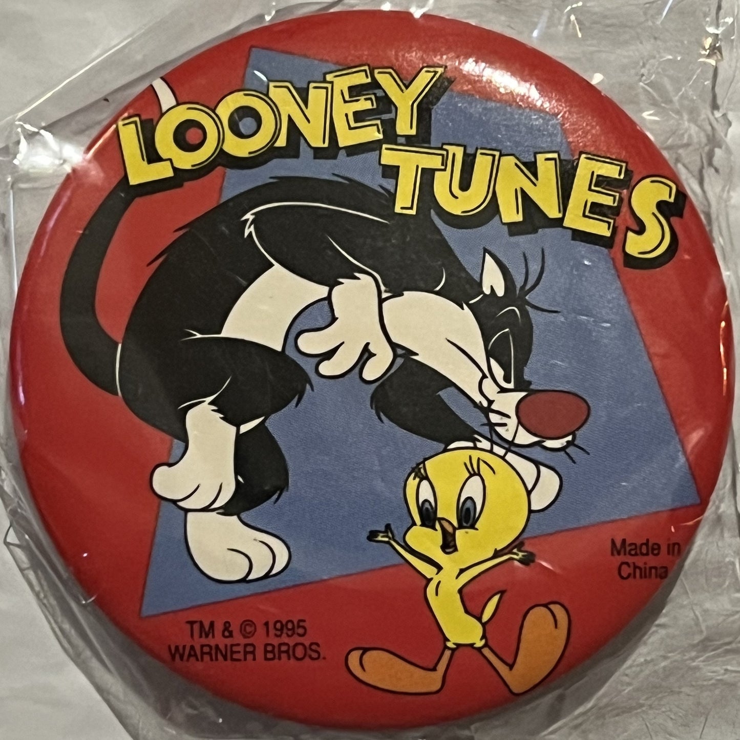 Sealed red circular pin featuring Sylvester cat and Tweety bird, yellow "LOONEY TUNES" text, Warner Bros 1995 copyright visib