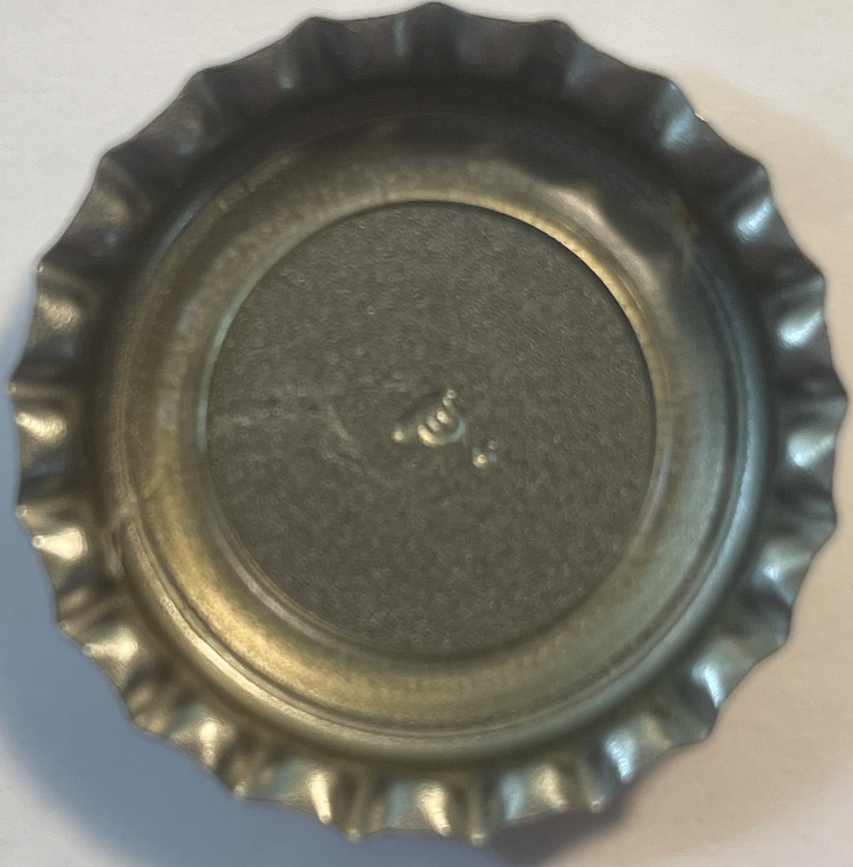 Inside of an unused Jolt Cola crown cap showing the fluted metal skirt and grey sealing disc
