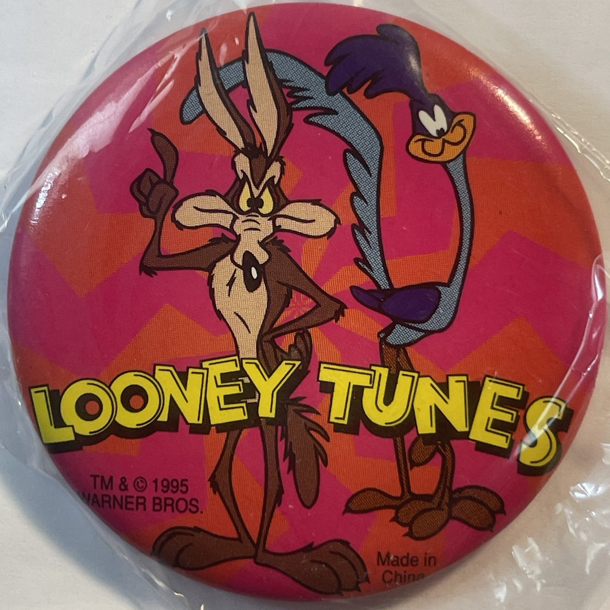 Circular red pin badge featuring cartoon Roadrunner and Wile E Coyote with "LOONEY TUNES" text and 1995 Warner Bros copyright