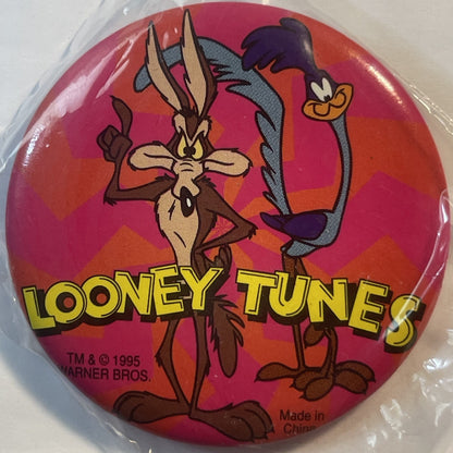 Circular red pin badge featuring cartoon Roadrunner and Wile E Coyote with "LOONEY TUNES" text and 1995 Warner Bros copyright
