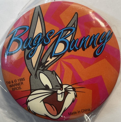 Circular pin featuring Bugs Bunny's face with blue "Bugs Bunny" text on orange and red geometric background, Warner Bros copy