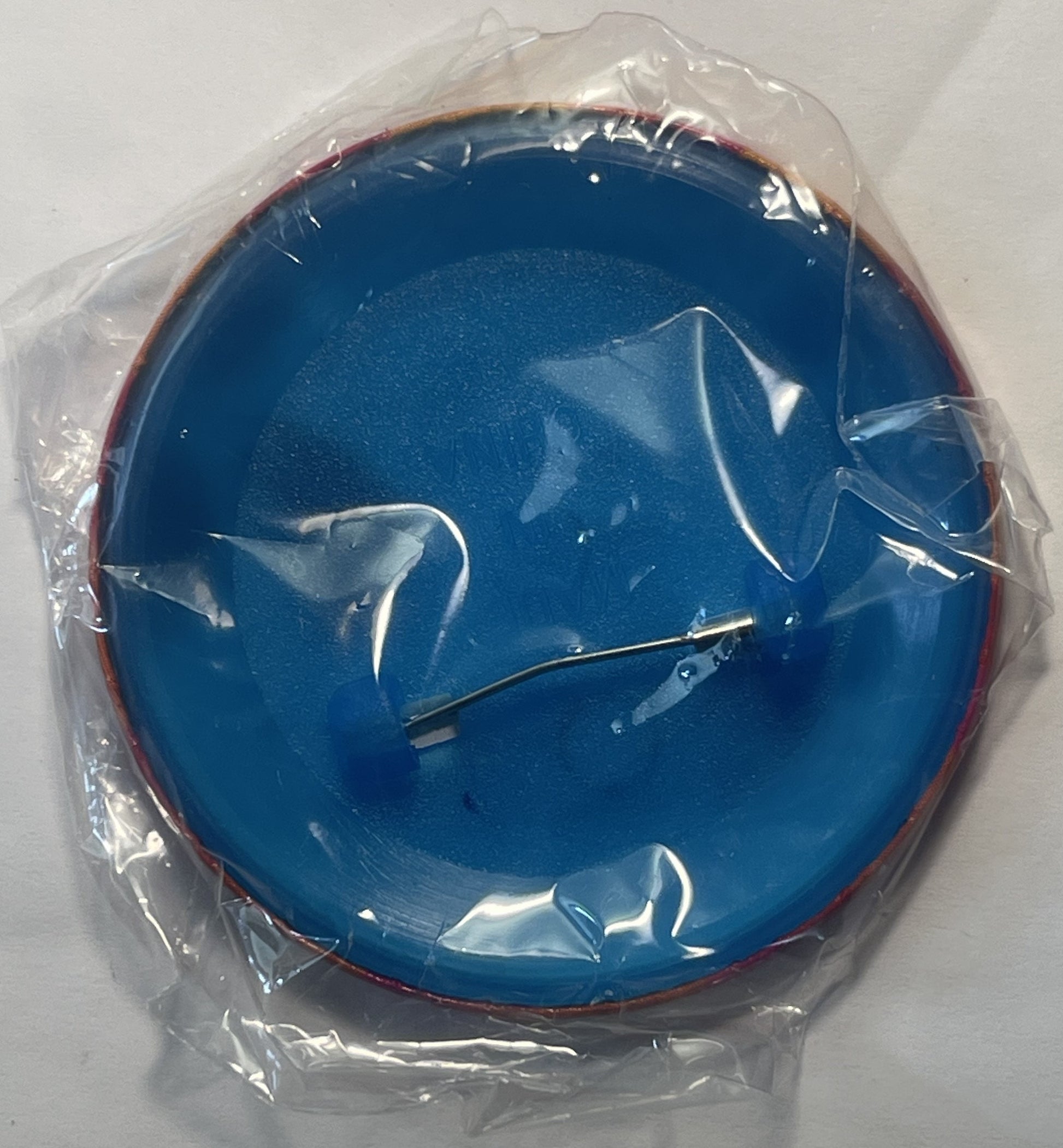 Blue circular pin in plastic packaging showing Bugs Bunny character design with metal backing and clasp visible from above