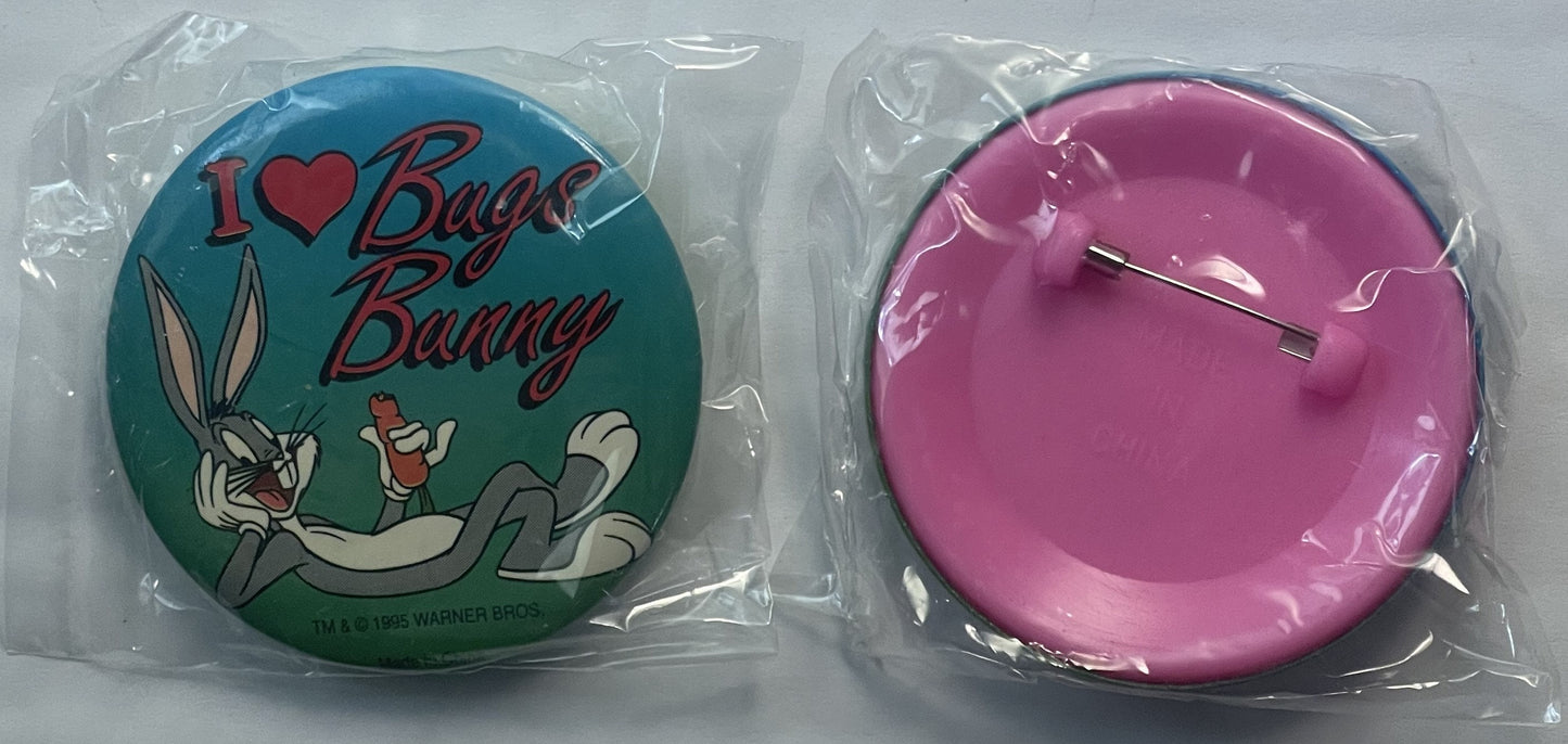Two unopened plastic-packaged pins: teal circular pin with "I ❤ Bugs Bunny" text and cartoon character, and plain magenta cir