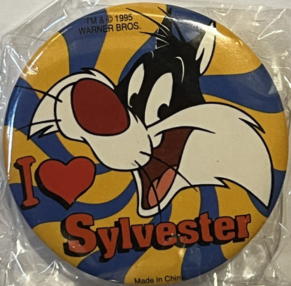 Sealed plastic package containing a circular pin featuring cartoon cat Sylvester with "I ♥ Sylvester" text on blue and gold s