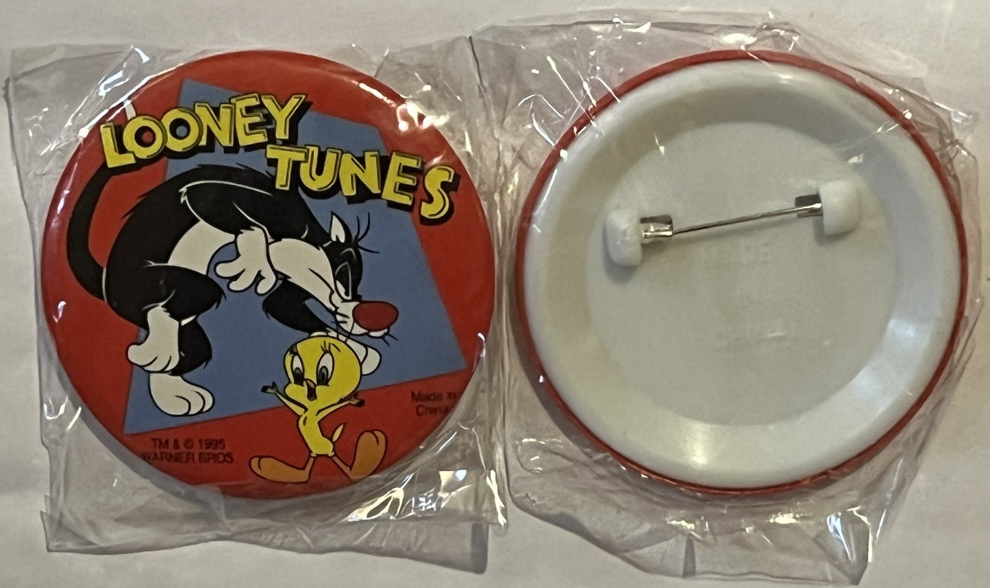 Two sealed plastic packages showing front and back of a 1995 Looney Tunes pin featuring Sylvester and Tweety, with red rim an