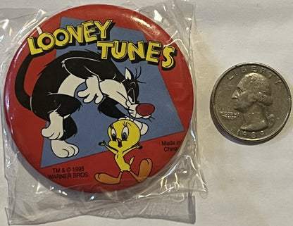 Unopened 1995 Warner Bros Looney Tunes pin featuring Sylvester and Tweety in plastic packaging, shown next to a quarter for s