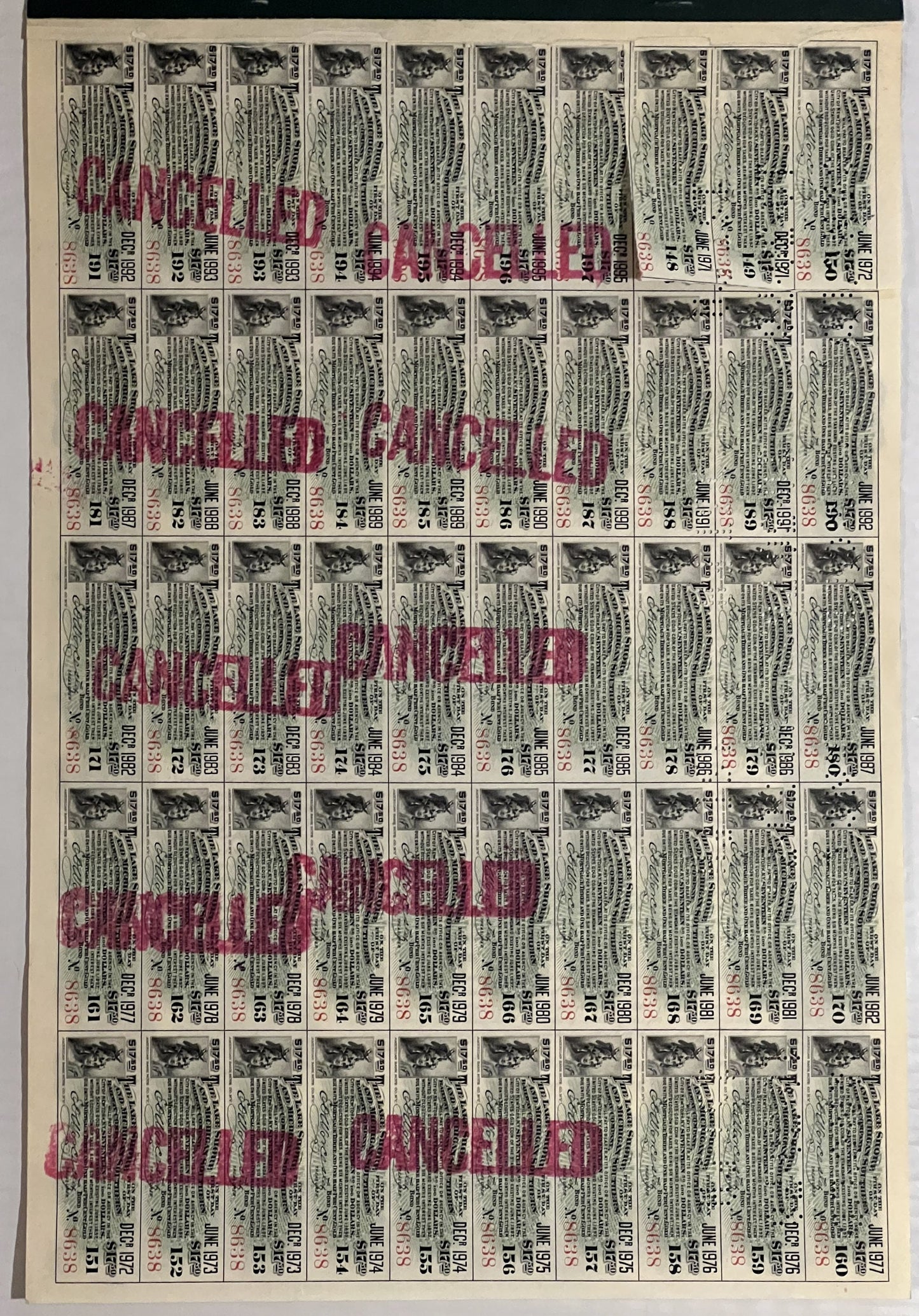 Full page of 50 vintage bond coupons with small train vignettes, printed text in black and red "CANCELLED" stamps overlaid di