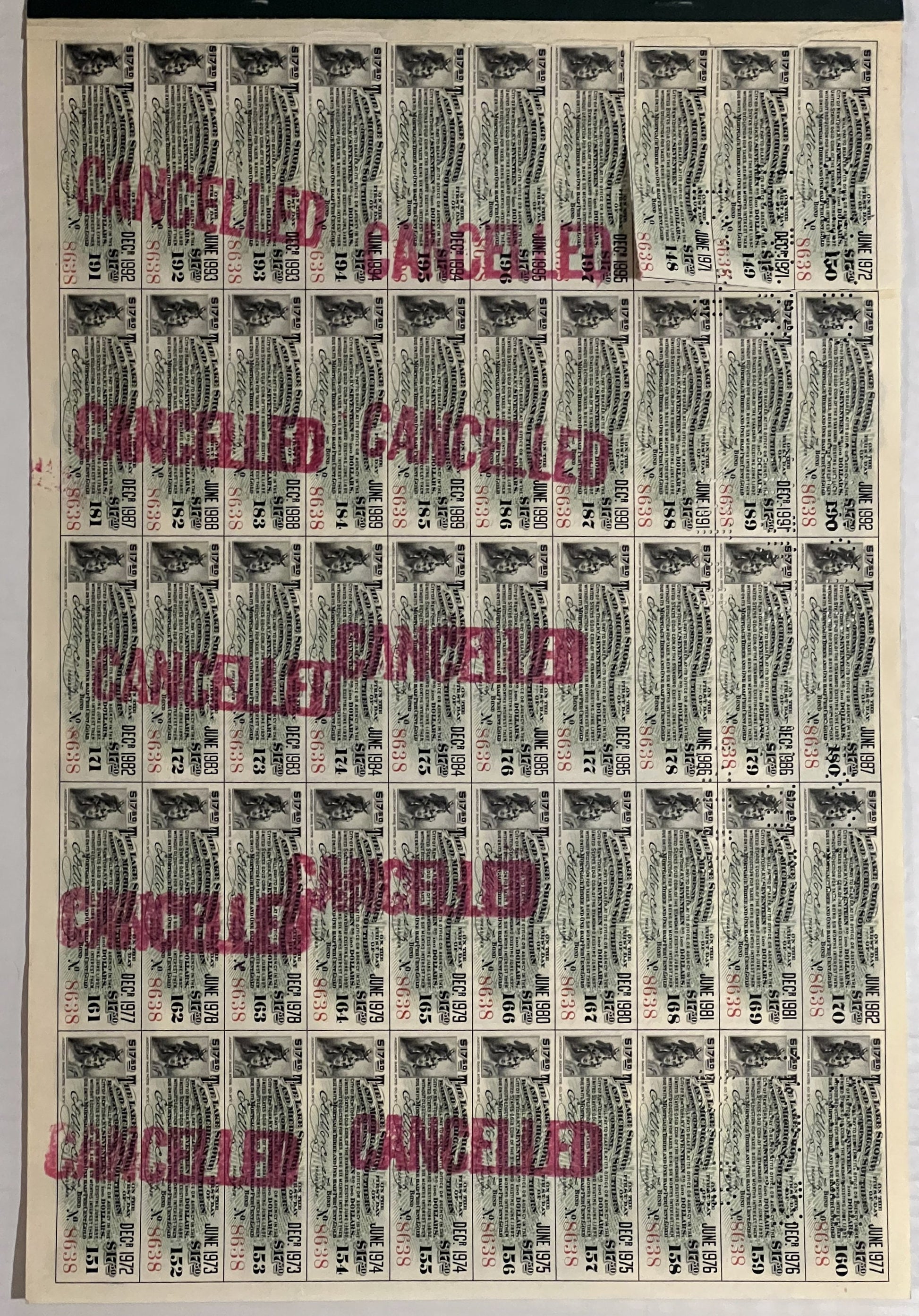 Full page of 50 vintage bond coupons with small train vignettes, printed text in black and red "CANCELLED" stamps overlaid di