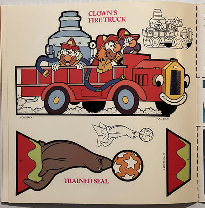 Open page spread from vintage Disney Dumbo press-out book showing colorful clown fire truck and trained seal illustrations wi