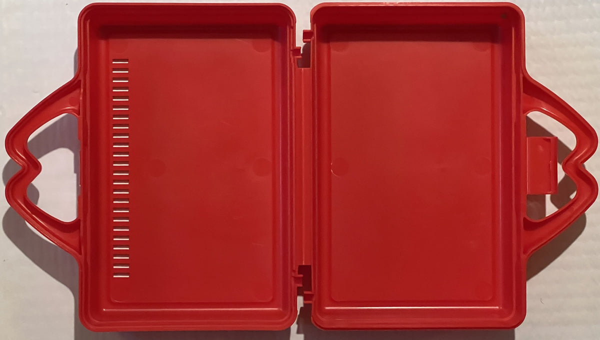 Red plastic hinged lunch box opened flat, showing interior compartments with measurement markings on left side, photographed 