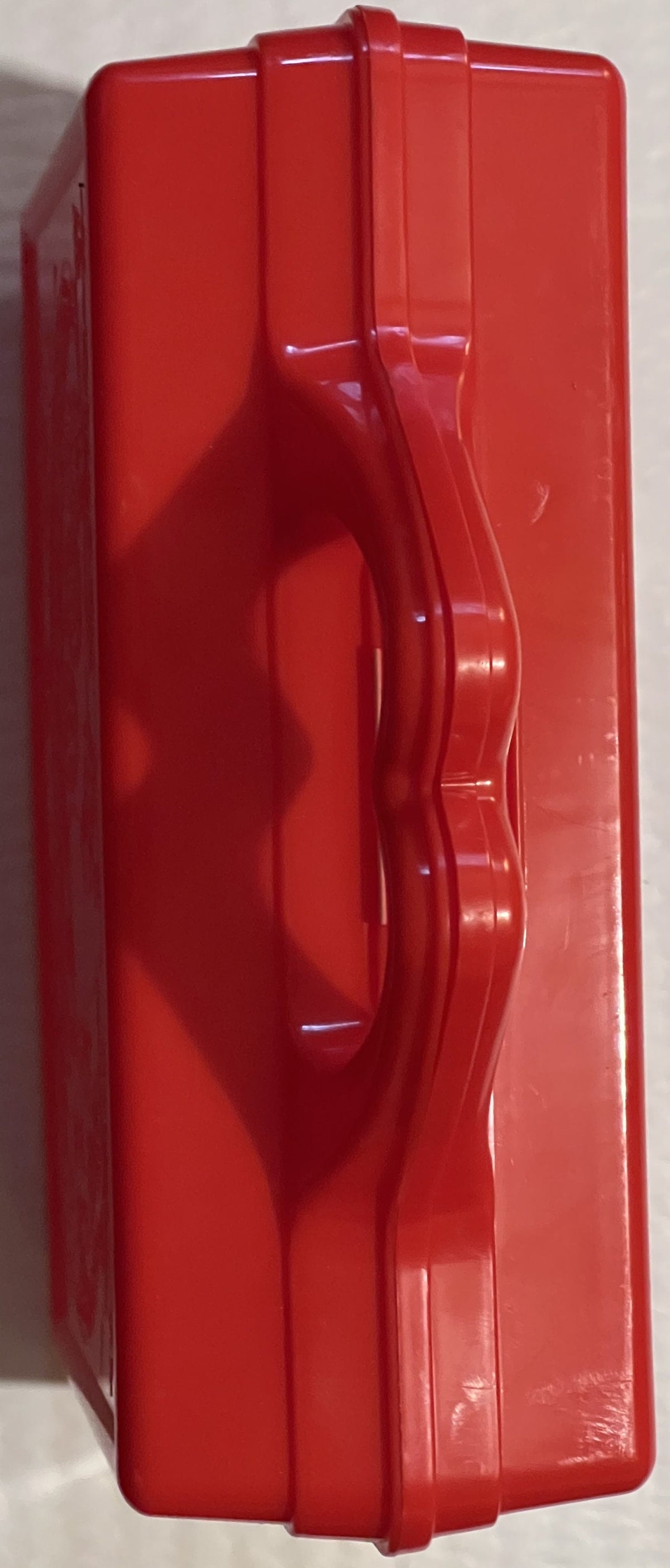 Bright red plastic lunch box with carrying handle, shown from back angle against white background