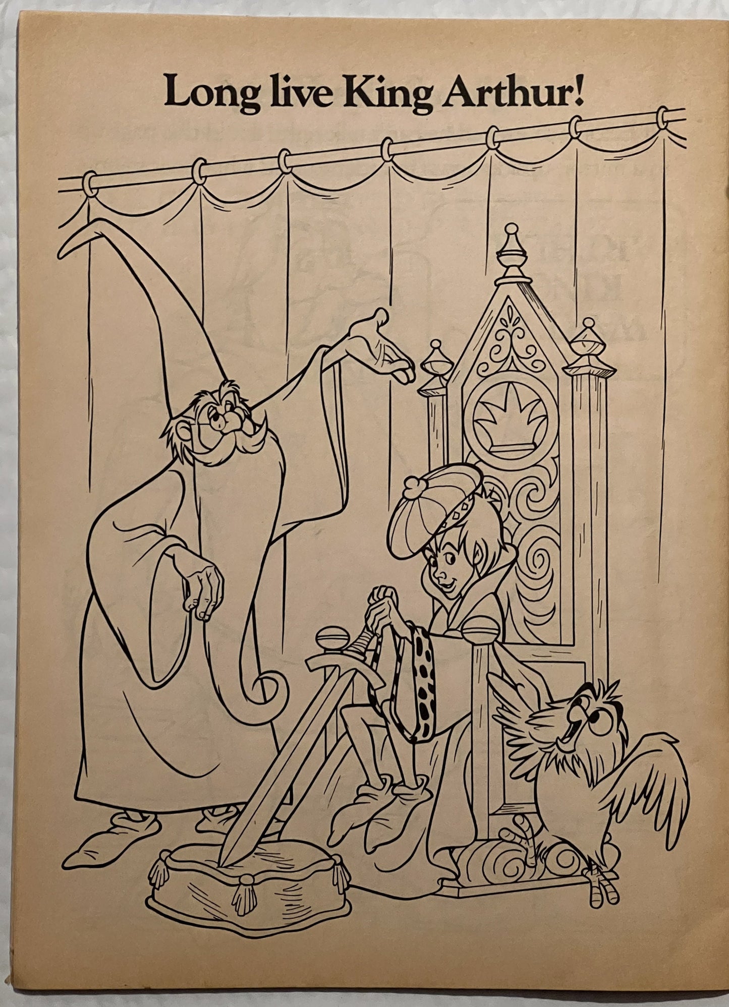 Beige book page with "Long live King Arthur!" headline and black line drawing of cartoon characters including a wizard, knigh