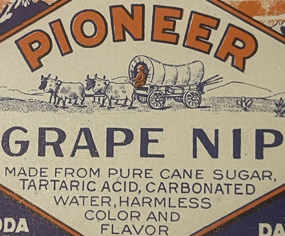 Vintage Pioneer Grape Nip label featuring orange text, covered wagon with oxen illustration, and ingredients list on cream