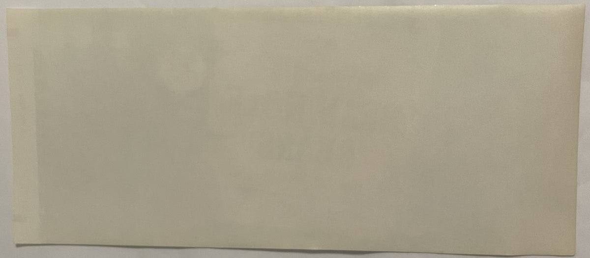 Blank cream-colored vintage label with dark line at bottom edge, photographed against gray surface