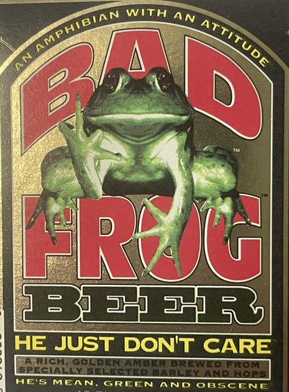 Vintage Bad Frog Beer label with green frog illustration, red text, gold border, and tagline "He Just Don't Care" on dark