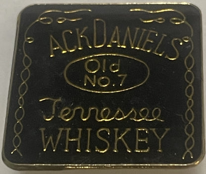 Square black enamel pin with gold embossed Jack Daniel's Old No. 7 Tennessee Whiskey branding and decorative border, shown fl