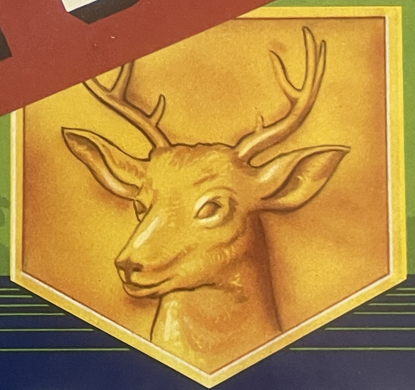 Embossed golden deer head in profile on yellow shield-shaped crate label with yellow border and striped background below