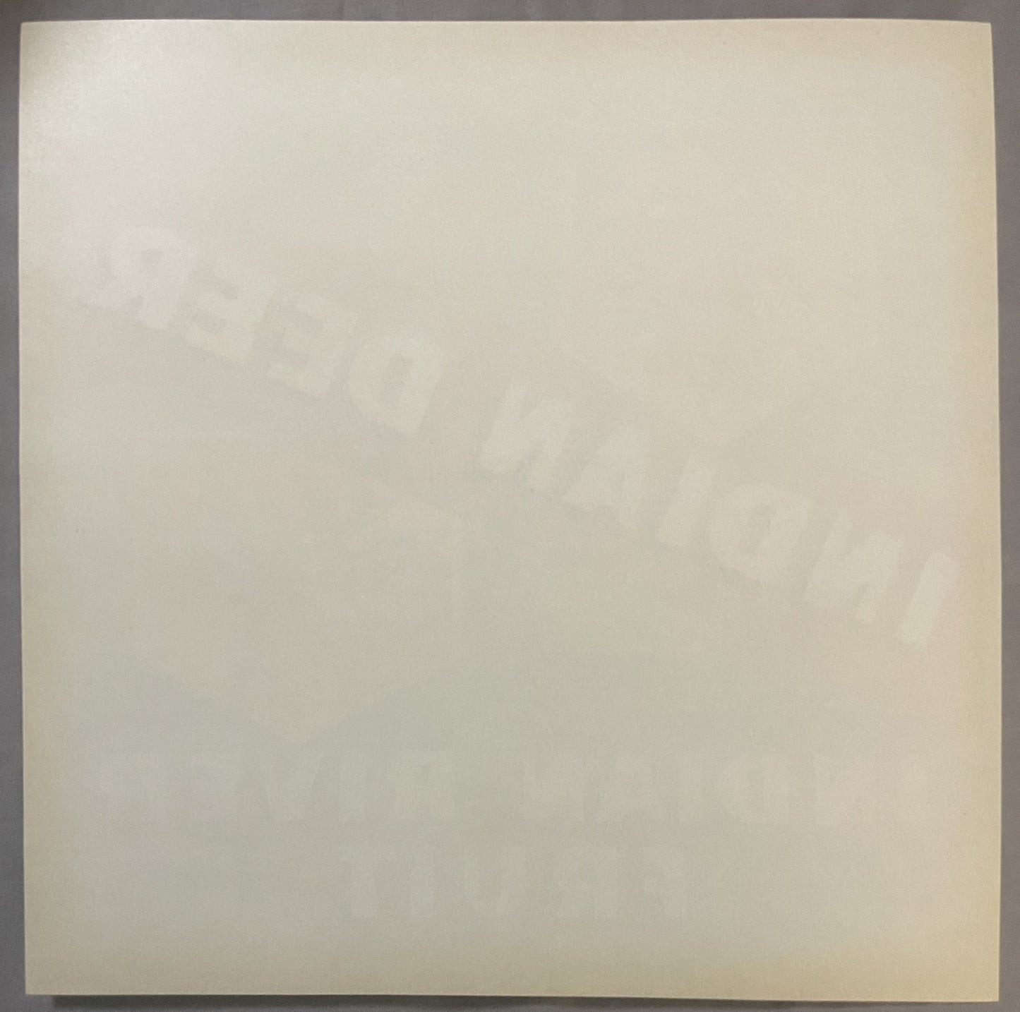 Cream-colored vintage fruit crate label with faint embossed or printed imagery, shown flat against gray surface