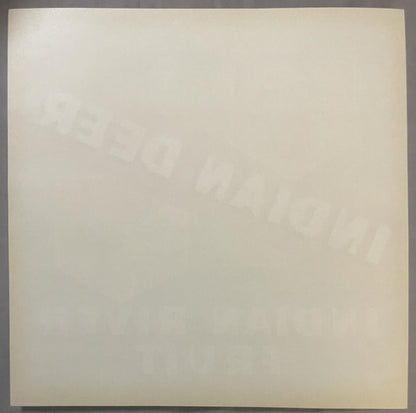 Cream-colored vintage fruit crate label with faint embossed or printed imagery, shown flat against gray surface
