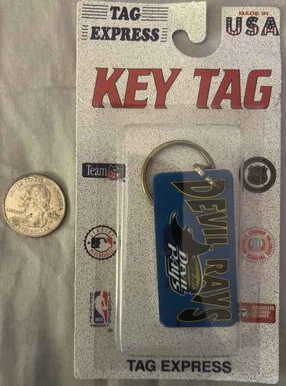 Vintage Tampa Bay Devil Rays keychain in original packaging next to a quarter for scale, showing blue rectangular tag with te