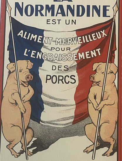 Close detail of the La Normandine back panel: two pigs stand upright holding the poles of a blue, white and red French flag lettered ALIMENT MERVEILLEUX POUR L'ENGRAISSEMENT DES PORCS