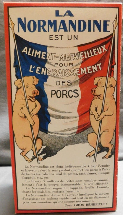 La Normandine box folded and standing, back panel: two pigs holding a French tricolor flag lettered ALIMENT MERVEILLEUX POUR L'ENGRAISSEMENT DES PORCS, red-bordered sales text below