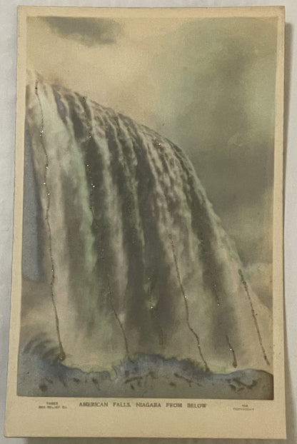 Sepia-toned vintage postcard showing American Falls at Niagara from below, with cascading water and mist, printed text at bot