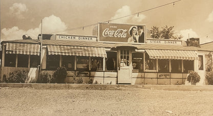 Vintage sepia-toned photograph of a 1940s-50s roadside diner with striped awnings, Coca-Cola signage, and "Chicken Dinner" an