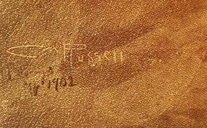 Close-up of tan linen fabric showing embossed text reading "Charles M. Russell" with woven texture visible